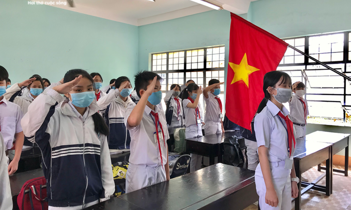 Học sinh chào cờ trong lớp học ngày trở lại trường