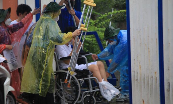 Thí sinh ngồi xe lăn đội mưa đi thi tốt nghiệp THPT