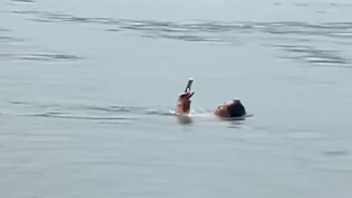 Video: Người đàn ông vừa bơi vừa lướt điện thoại
