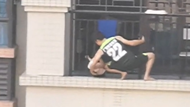 Video: Người đàn ông ở Trung Quốc treo mình giải cứu em bé mắc kẹt trên tầng 7