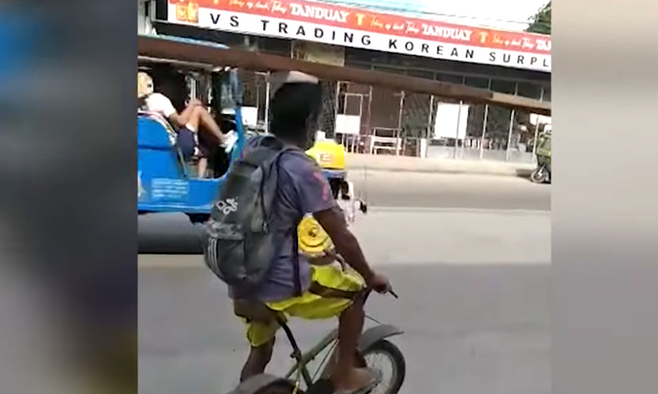 Người đàn ông đi xe đạp dùng đầu vận chuyển thanh gỗ ở Philippines 