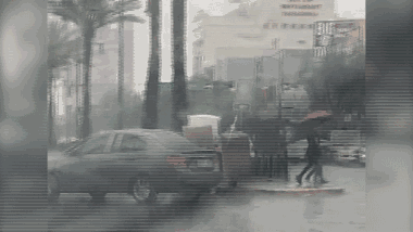 Thanh niên dùng 'bộ giáp' che mưa băng qua đường