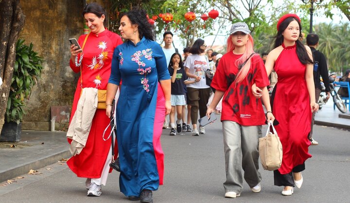 Nữ du khách ngoại quốc thướt tha áo dài tản bộ phố cổ Hội An dịp Tết Nguyên đán