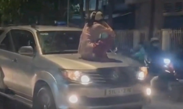 Người phụ nữ ngồi trên nắp capo ô tô chạy trên đường ở Bình Dương 