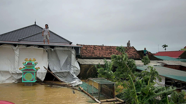 Cả thị trấn chìm trong lũ, người dân Lệ Thuỷ trèo lên mái nhà nhận đồ cứu trợ 