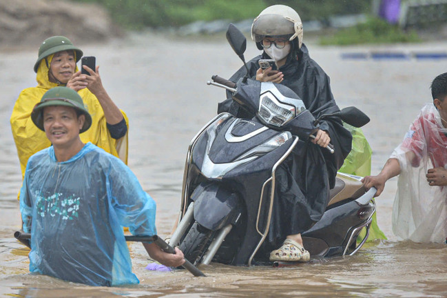 Ngập tới bụng trên quốc lộ, xe kéo 'cõng' xe máy vượt biển nước