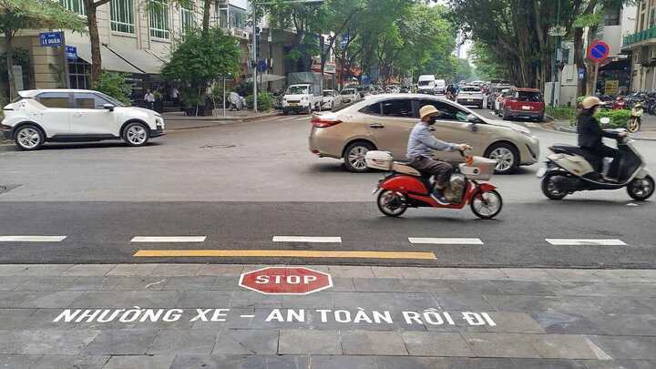 Cục CSGT sơn chữ trên đường nhắc tài xế dừng lại khi đi từ ngõ ra đường lớn