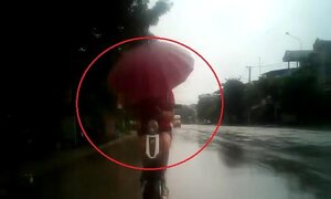 Thiếu nữ đi xe đạp điện cầm ô, đâm sầm vào đuôi ô tô