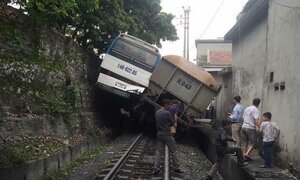 Băng qua đường ray, xe chở công nhân bị tàu hỏa kéo lê chênh vênh trên mép đá