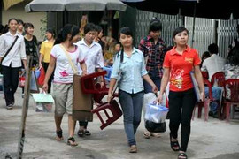 Nữ sinh mang xô, chậu, ghế, bảng đến trường thi