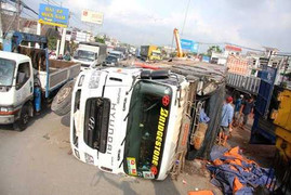 Xe tải lật, gần 20 tấn gỗ đổ xuống đường