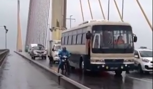 Xe khách biển xanh chắn gió cho xe máy qua cầu Bãi Cháy trong mưa bão