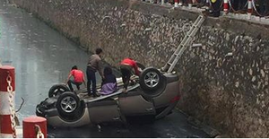 Dân cạy cửa cứu tài xế trong chiếc ô tô 'phơi bụng' dưới kênh nước