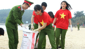 Chiến sỹ công an trẻ mặc áo cờ đỏ sao vàng làm sạch môi trường biển