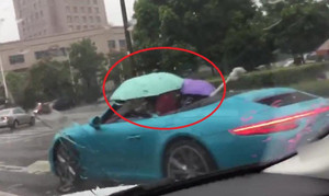 Bi hài cảnh 'dân chơi' lái siêu xe Porsche mui trần cầm ô che mưa