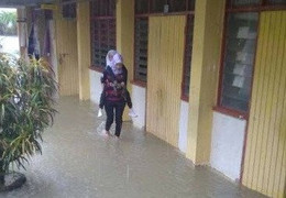 Nữ giáo viên Malaysia cõng học sinh qua nước lũ