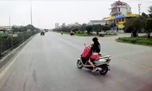 Nữ 'ninja' chở con nhỏ vừa lái xe vừa buông tay cởi áo mưa trên quốc lộ khiến người xem thót tim
