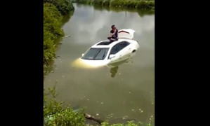 Tài xế khoanh chân ngồi trên nóc ôtô ngập nước chờ cứu hộ