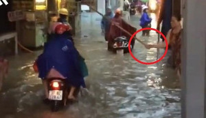 Clip: Người phụ nữ đứng trên phố ngập, lăm le cầm gậy vụt người đi đường