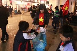 Trẻ em dọn rác trên phố trung tâm Hà Nội sau khi người hâm mộ 'đi bão' mừng Việt Nam vô địch
