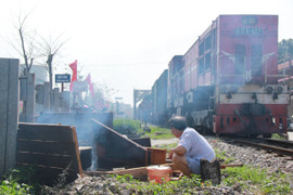 Người Hà Nội bắc bếp luộc bánh chưng cạnh đường ray tàu hỏa chạy qua