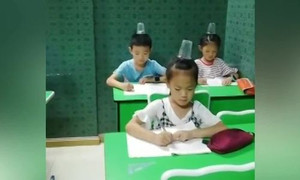 Học sinh Trung Quốc giữ thăng bằng cốc trên đầu để thẳng lưng khi viết