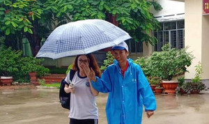 Ảnh: Sinh viên TP.HCM đội mưa che dù cho thí sinh làm thủ tục thi THPT Quốc gia 2019