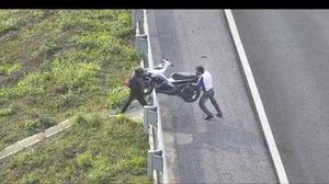 Đi nhầm vào cao tốc, 2 thanh niên chật vật khiêng xe máy qua rào chắn