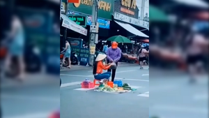 Người phụ nữ ngồi bán trái cây giữa lòng đường mặc xe cộ qua lại tại Bình Dương