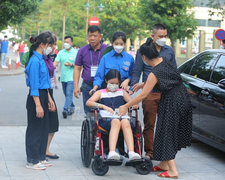 Học sinh ngồi xe lăn, có bác sĩ đi kèm đến phòng thi xét tuyển vào lớp 6