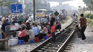 Thản nhiên ngồi ăn uống ngay cạnh đường ray tàu hỏa ở Hà Nội