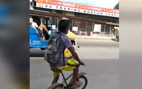 Người đàn ông đi xe đạp dùng đầu vận chuyển thanh gỗ ở Philippines 