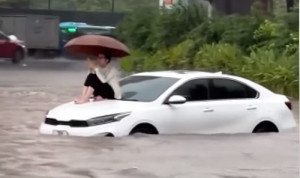 Cô gái ngồi trên nắp capo ô tô lướt điện thoại giữa 'biển nước' Hà Nội ngày lụt