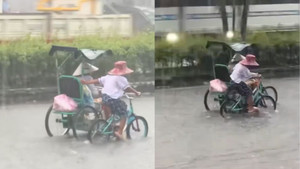 Xúc động em nhỏ còng lưng đạp xe, đẩy xe người khuyết tật khi mưa to, đường ngập