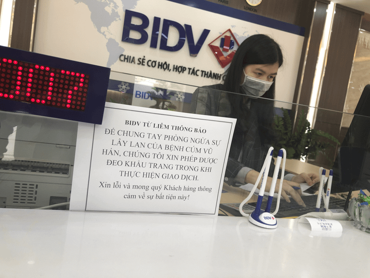 Nhân viên ngân hàng, siêu thị đồng loạt đeo khẩu trang phòng ngừa virus corona - 1