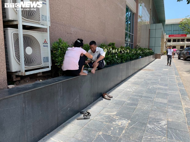 Người nhà bệnh nhân ăn cơm dưới chân tòa nhà, ngủ ở gốc cây trốn nắng nóng - 12