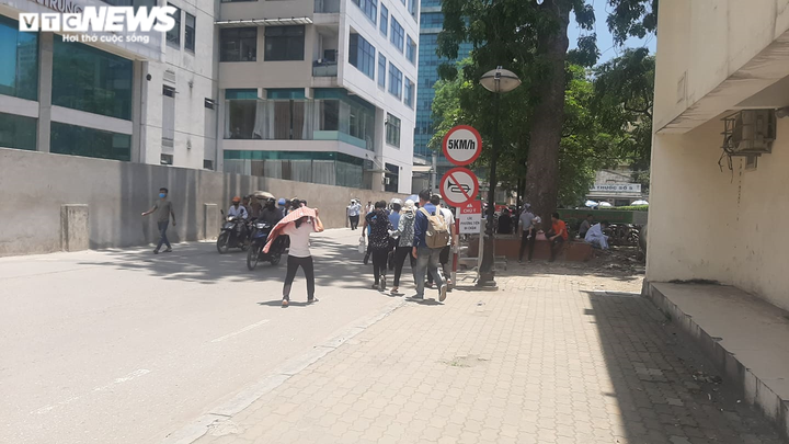 Người nhà bệnh nhân ăn cơm dưới chân tòa nhà, ngủ ở gốc cây trốn nắng nóng - 1