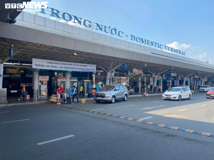 29 Tết, sân bay Tân Sơn Nhất thưa thớt, hành khách kín mít đồ bảo hộ - 1