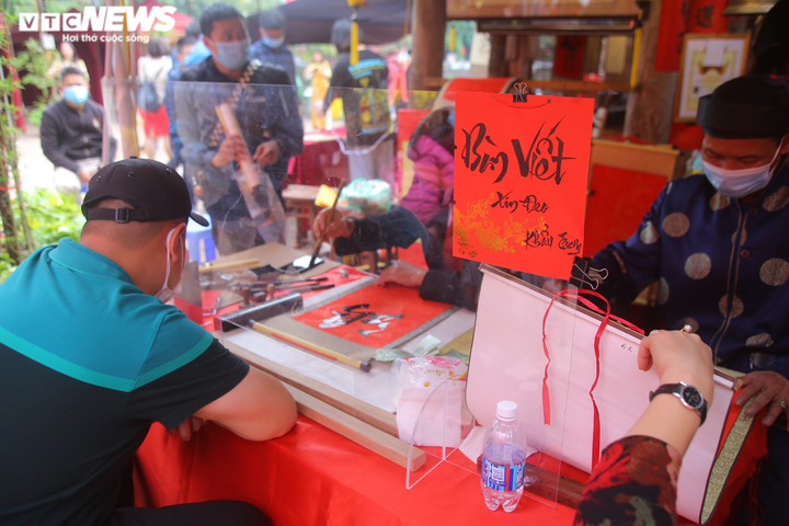 Ảnh: Ông đồ cho chữ qua tấm chắn tại Văn Miếu ngày mùng 2 Tết - 10