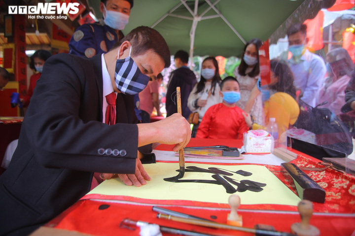 Ảnh: Ông đồ cho chữ qua tấm chắn tại Văn Miếu ngày mùng 2 Tết - 5