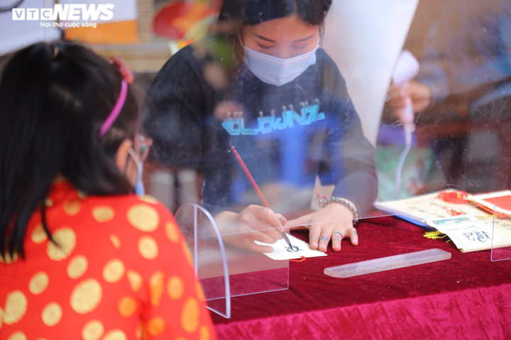 Ảnh: Ông đồ cho chữ qua tấm chắn tại Văn Miếu ngày mùng 2 Tết - 6