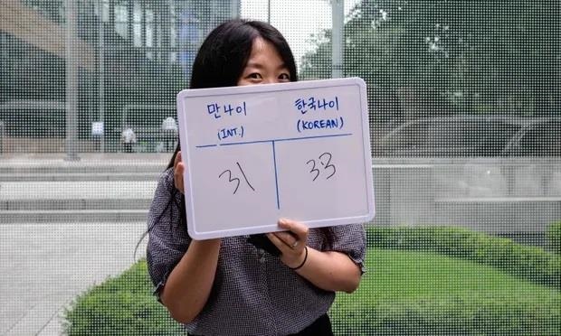 Cô Kim Jin-sil cầm tấm bảng ghi tuổi quốc tế của cô là 31 và tuổi Hàn Quốc là 33. Ảnh: AFP