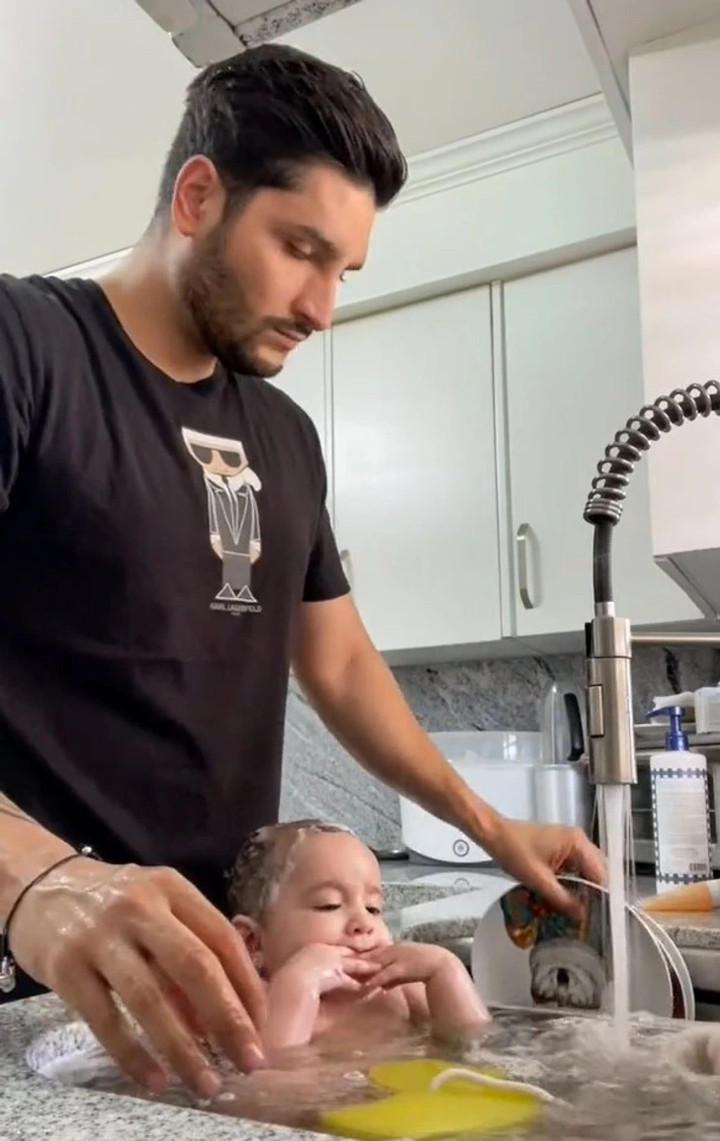 Em bé hồn nhiên mút tay trong bồn rửa bát.