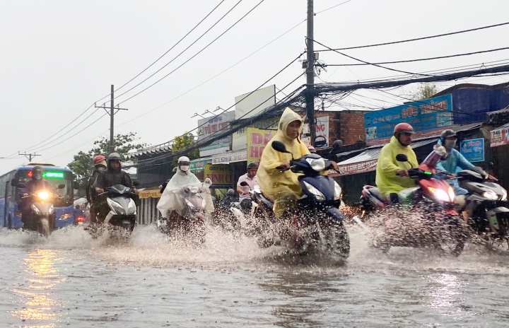Tại quốc lộ 50 (huyện Bình Chánh) người dân di chuyển khó khăn do nước lênh láng sau cơn mưa. (Ảnh: Lương Ý)