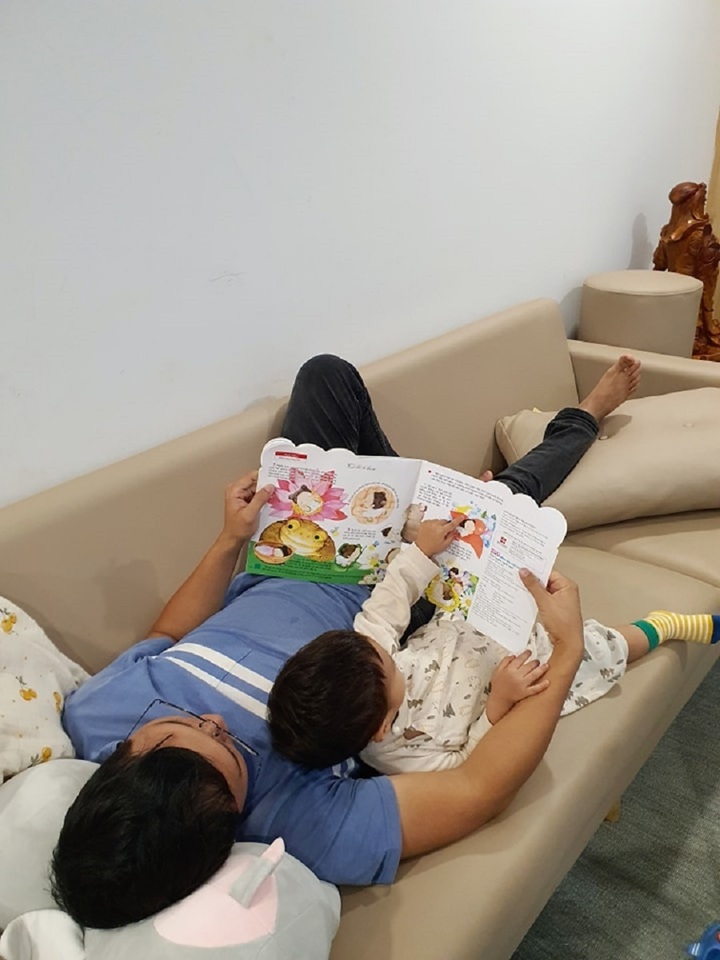 Hai bố con nằm đọc sách mỗi buổi tối.