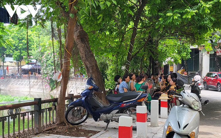 Một đoạn vỉa hè chật kín bàn ghế, xe cộ, chen chúc sau hàng cột đang làm dở, khiến đoạn đường này không còn chỗ trống để người dân qua lại.