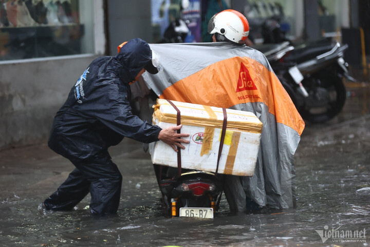 Những người chở hàng hóa cồng kềnh bị bất ngờ với cơn mưa khi đi giữa đường và gặp nhiều khó khăn.