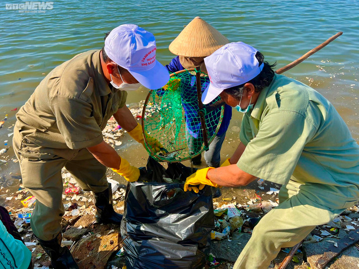 Người dân phối hợp với lực lượng chức năng dùng vợt lưới vớt rác cho vào bao để đưa đi xử lý.