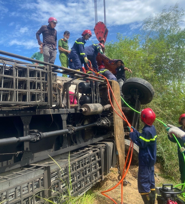 Lực lượng chức năng giải cứu tài xế mắc kẹt trong cabin của chiếc xe tải bị lật nghiêng dưới ruộng. (Ảnh: Đ.T)