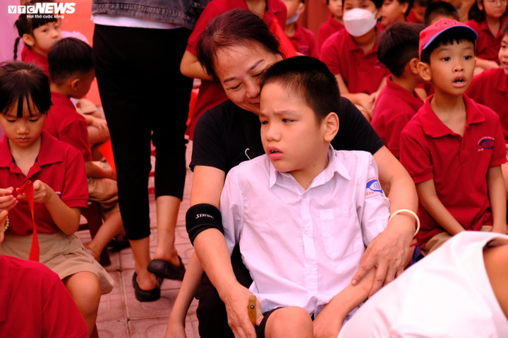 Bà Nguyễn Thị Nhã ôm cháu ngoại vào lòng giữa sân trường. Bà cho biết, vì sinh non ở tuần thứ 25 nên cơ thể cháu yếu ớt, lại thêm chứng bại não thể co cứng nên không thể đi, đứng.